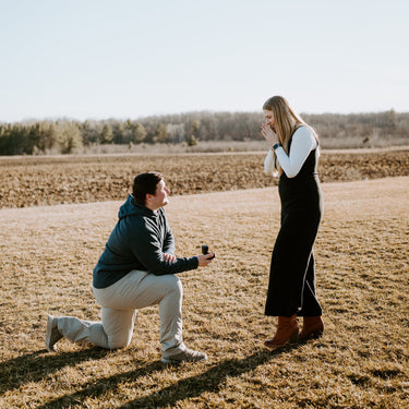 Man proposing to a woman in a field on a sunny day