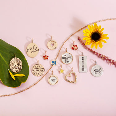 Collection of various pendants on a pink background with a sunflower and green leaf.